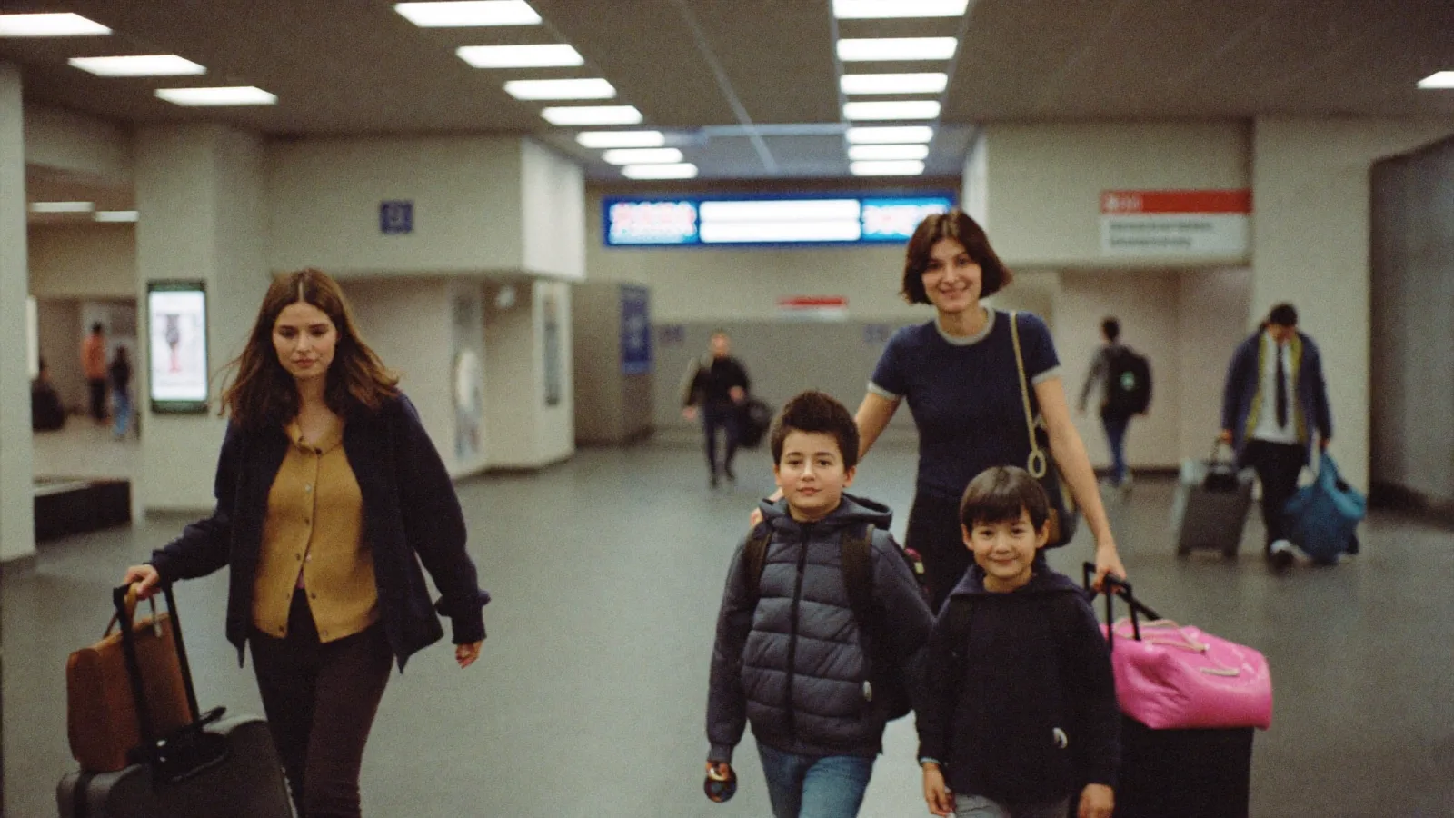 A family arriving at a UK airport arrivals hall with luggage