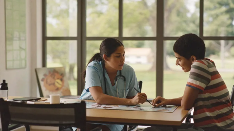 A learning disability nurse supporting a young adult with a communication board in a community setting