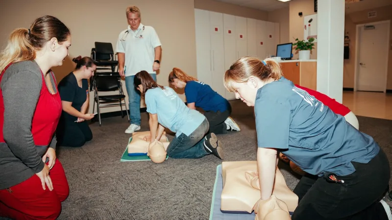 Staff practising CPR on a resuscitation manikin during a basic life support training session