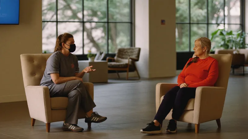 A support worker sitting and talking with a service user in a calm communal lounge