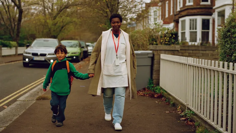 A parent in healthcare uniform walking a child to school before a shift