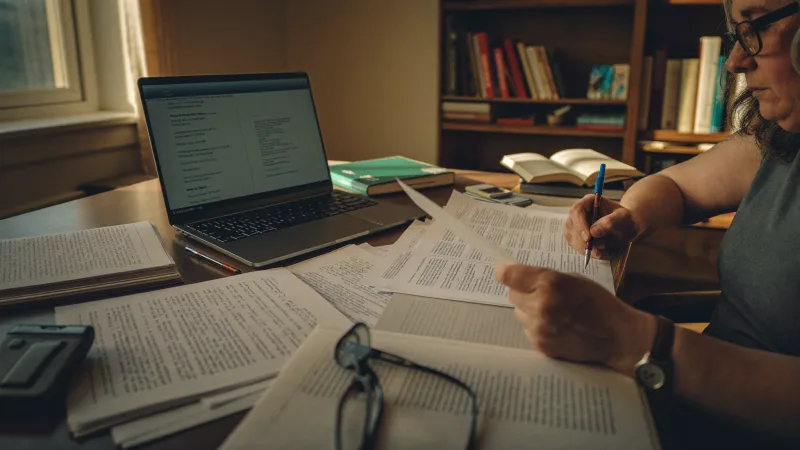 An older healthcare worker reviewing pension paperwork at a desk at home