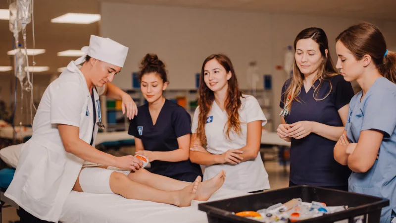 A practice educator demonstrating a clinical technique to a small group of students