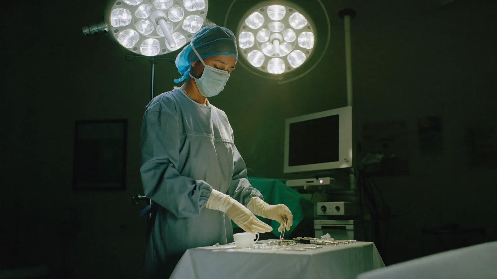 A scrub nurse arranging instruments on a sterile trolley in an operating theatre