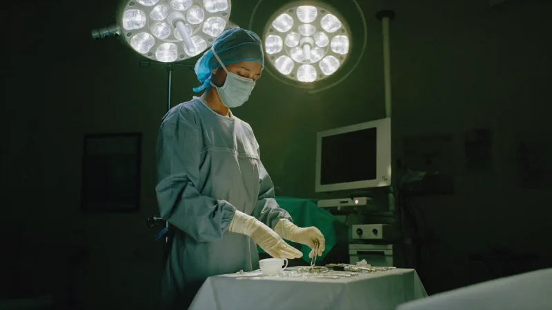A scrub nurse arranging instruments on a sterile trolley in an operating theatre